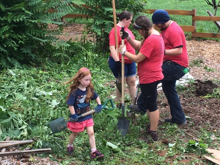 The First Year Seminar class `Gardens in Literature` partners with a community garden. Students are shoveling mulch.