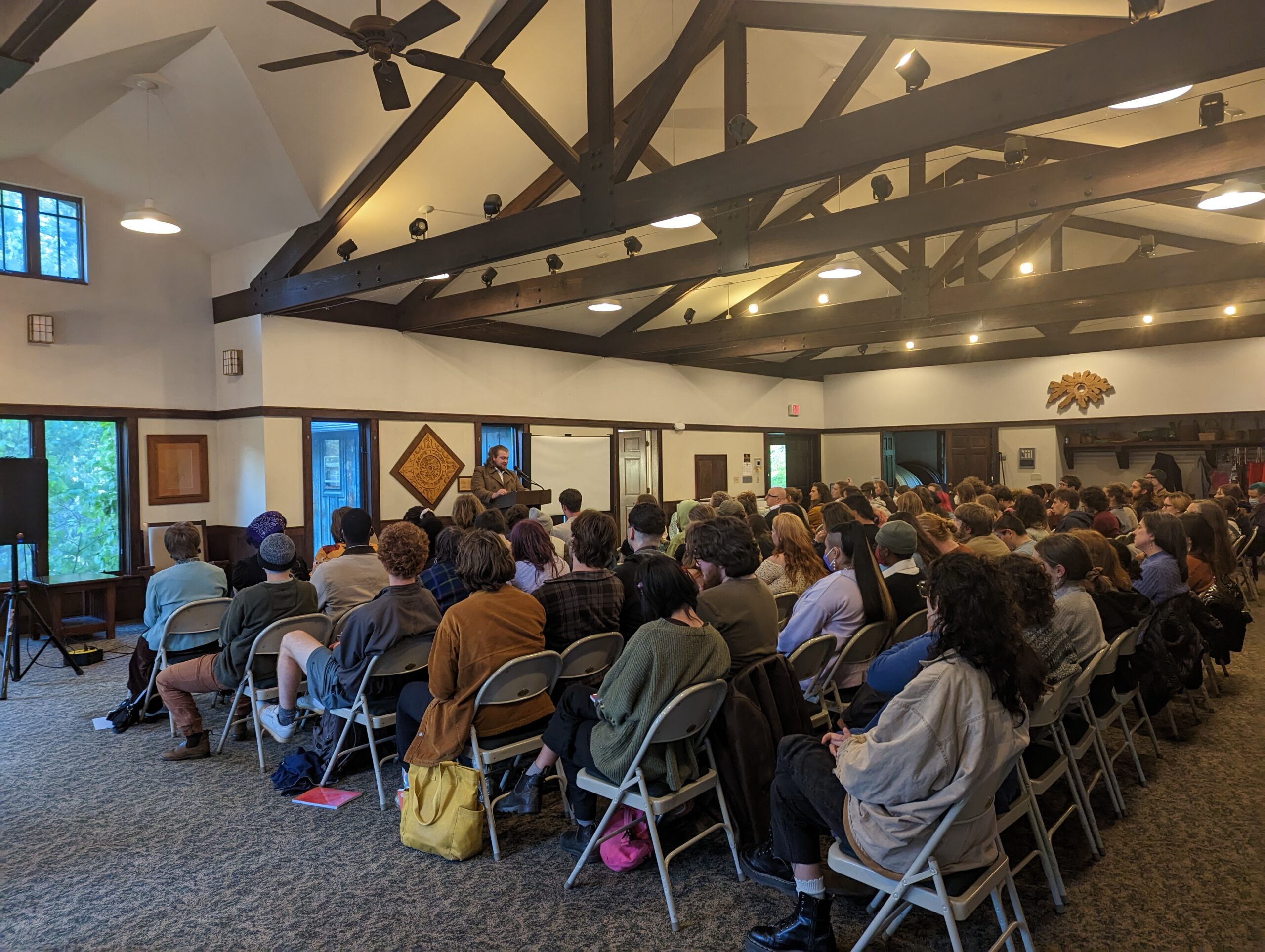 A large group of students gather for a creative writing event. They are seating facing a single speaker.