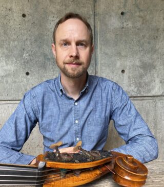 Faculty Member Kevin Kehrberg sits behind a instrument outside of Kitteridge.