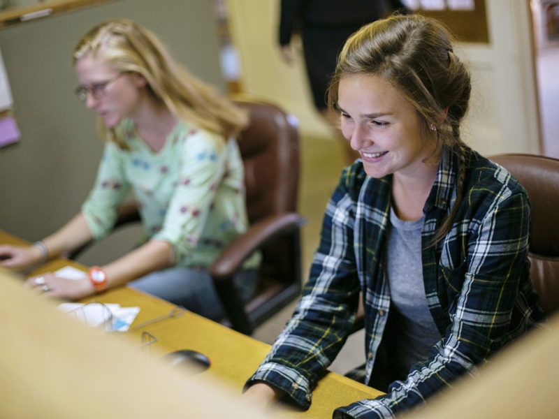 Admission Crew students smiling working on computers