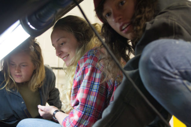 Sophomores Charlotte Surface and Corinna Steinrueck and senior Savannah Livengood work on a vehicle inside the College Autoshop.