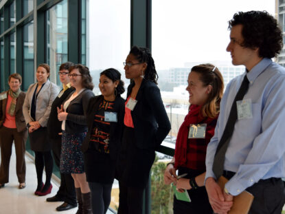 Students stand in front of a window wearing formal clothes