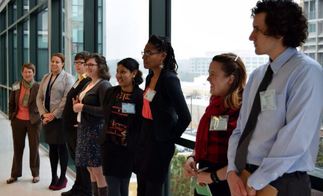 Students stand in front of a window wearing formal clothes