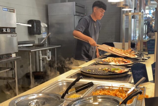 A dining crew student making pizza