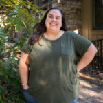 Faculty Member Liz Benavides stands smiling outside of Orr Cottage.