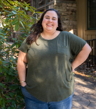 Faculty Member Liz Benavides stands smiling outside of Orr Cottage.