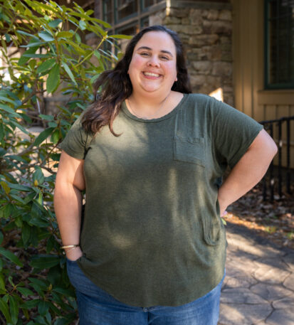 Faculty Member Liz Benavides stands smiling outside of Orr Cottage.