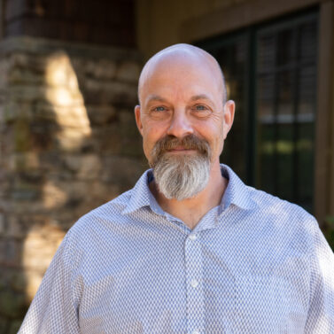 Faculty Member Jack Ingelman stands smiling outside of Orr Cottage.