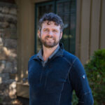 Faculty Member Matthew Vossler stands smiling outside of Orr Cottage.