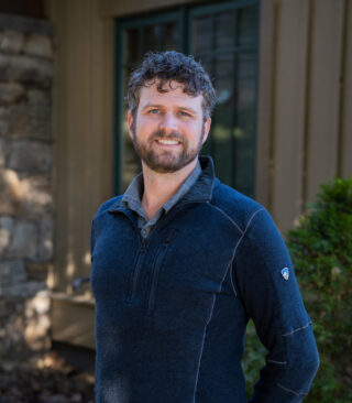 Faculty Member Matthew Vossler stands smiling outside of Orr Cottage.