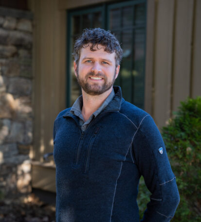 Faculty Member Matthew Vossler stands smiling outside of Orr Cottage.