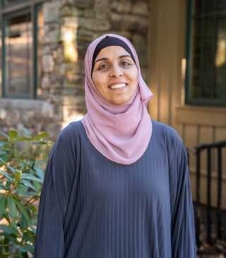 Faculty Member Nancy Matar stands smiling outside of Orr Cottage.