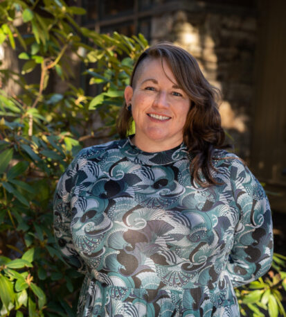 Faculty Member Scotti Norman stands smiling outside of Orr Cottage.