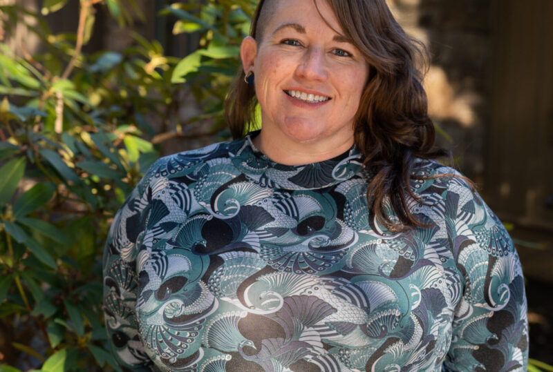 Faculty Member Scotti Norman stands smiling outside of Orr Cottage.