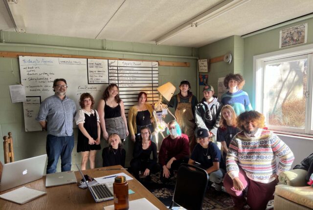 Group photo of Fall 2022 Echo Newspaper crew. Students and Jay Lively gather together smiling in their office.