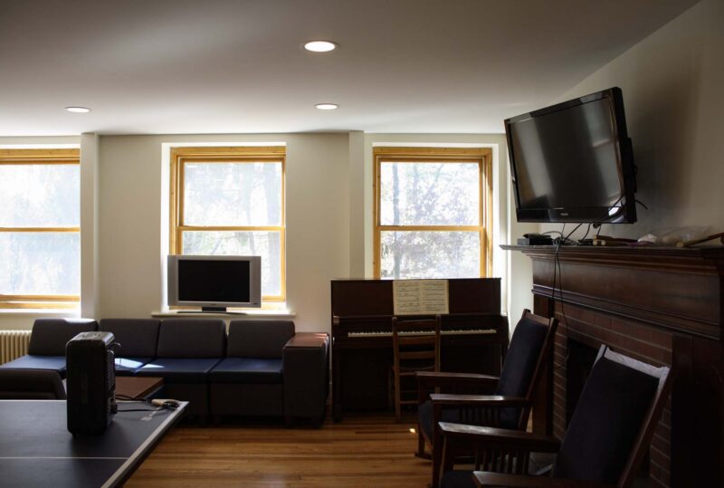The furnished common room of sage dorm with flat screen tv, chairs, and couch.