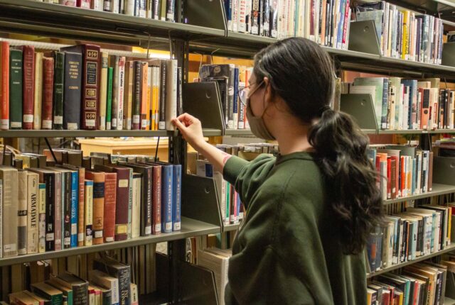 A Library Crew student putting books away