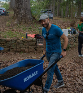 History professor Dr Robert Miller pushes a wheelbarrow full of mulch.