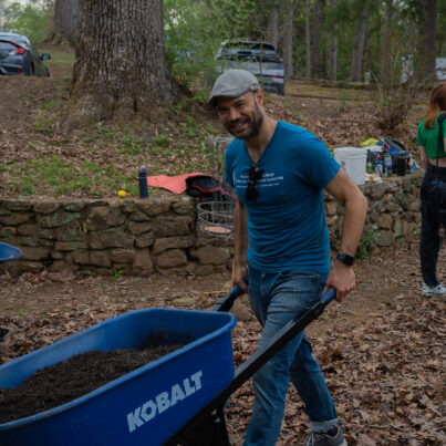 History professor Dr Robert Miller pushes a wheelbarrow full of mulch.
