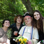 A graduate poses with three other people smiling.