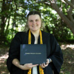 A graduate holds their degree smiling.