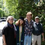 A graduate is joined by three people in a photo smiling.