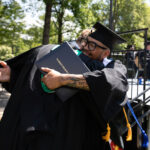 A grad hugs Dean of Work Paul Bobbit