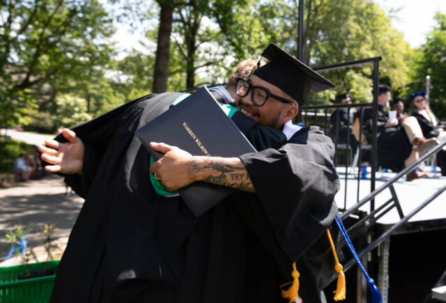 A grad hugs Dean of Work Paul Bobbit