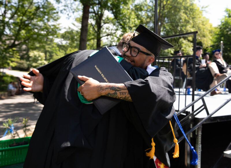 A grad hugs Dean of Work Paul Bobbit