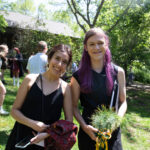 A grad stands with another person smiling