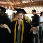 A graduate stands smiling in the pavilion