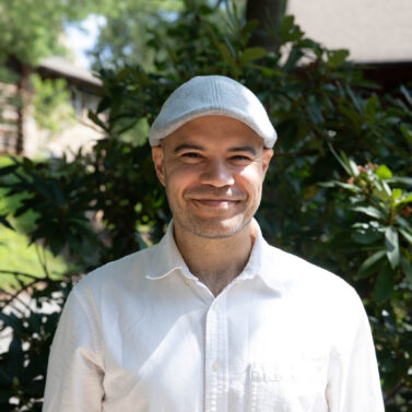 Dr. Robert Miller stands smiling in front of Orr Cottage.