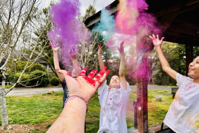 Asian Culture Club's Holi Festival Celebration. Hands throw colorful dust into the air.