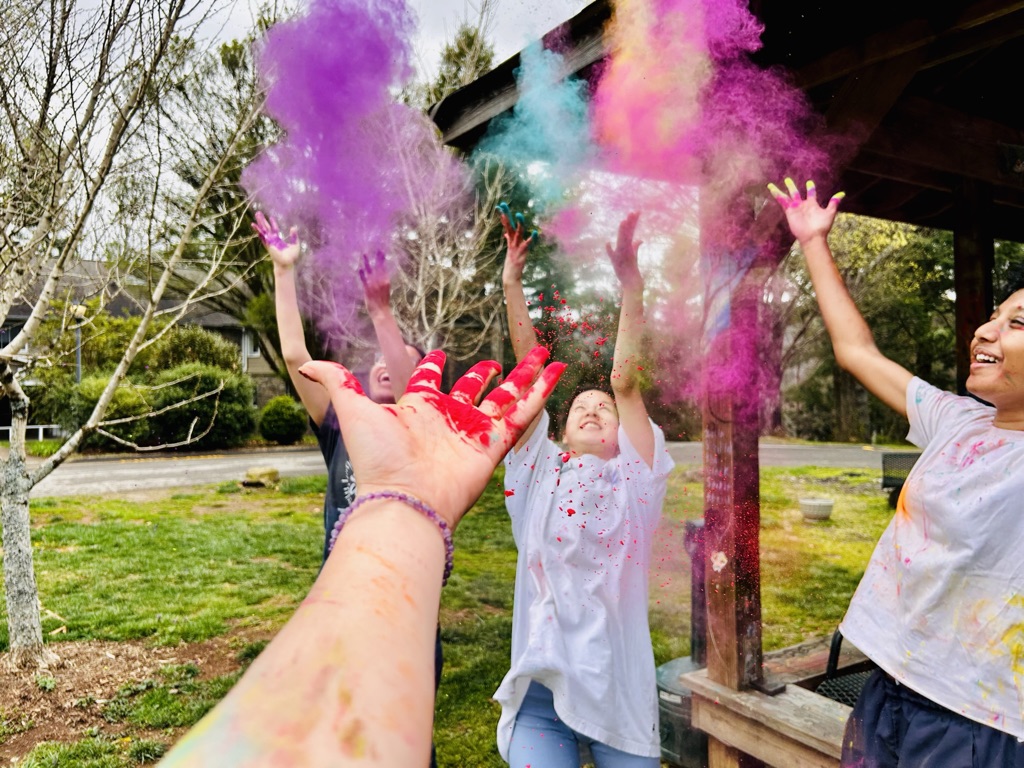 Asian Culture Club's Holi Festival Celebration. Hands throw colorful dust into the air.