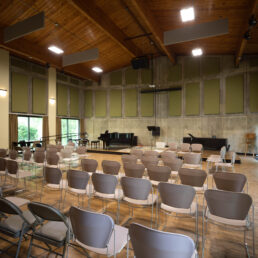 The recital hall has five rows of chairs facing a stage. There is sound padding covering the walls.