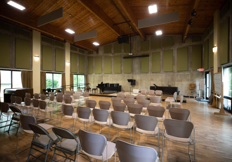 The recital hall has five rows of chairs facing a stage. There is sound padding covering the walls.