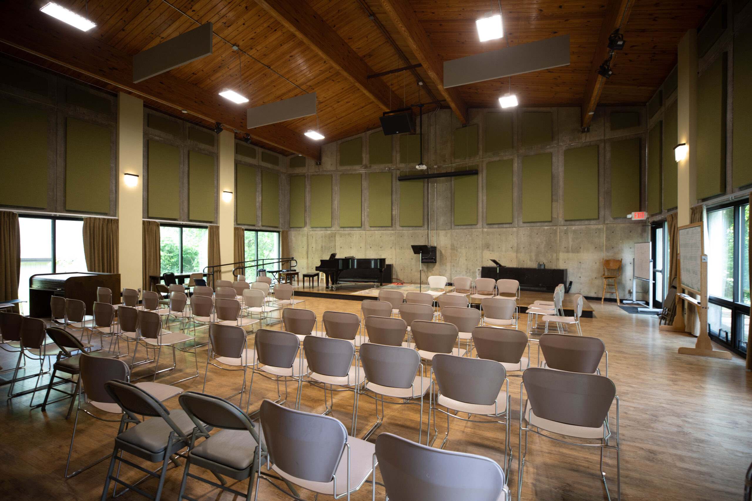The recital hall has five rows of chairs facing a stage. There is sound padding covering the walls.