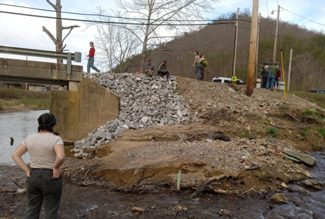 Students stand on the washout of a riverbank in Kentucky.