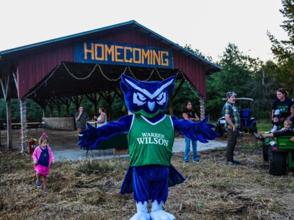 The owl mascot stands in front of the homecoming barn