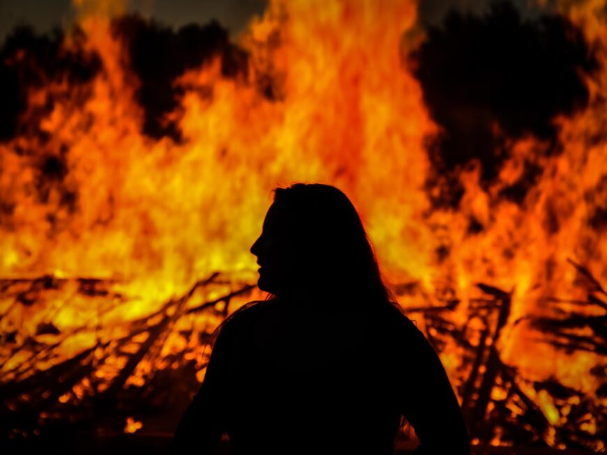 A silhouette of a student sitting in front of a bonfire
