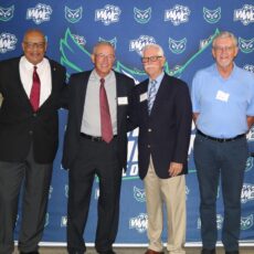 People gather together for a photo in front of the Warren Wilson Athletics press board.