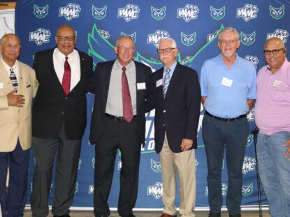 People gather together for a photo in front of the Warren Wilson Athletics press board.