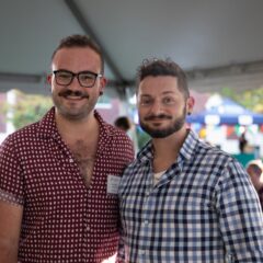 Two alumni stand together for a photo at the homecoming barbeque