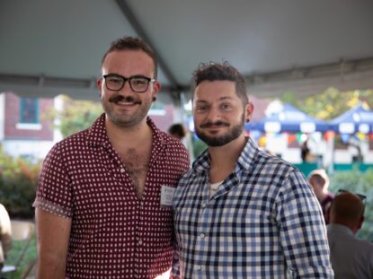 Two alumni stand together for a photo at the homecoming barbeque