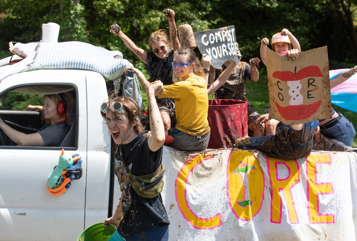 Core Crew students on their parade `float`. They hold signs that say Core and Compost yourself. They are covered in compost.