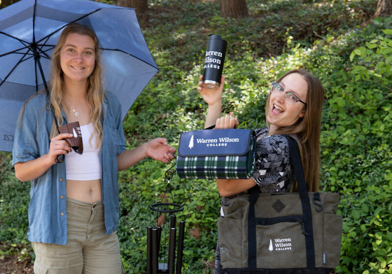 Two students stand showing warren wilson branded merchandise