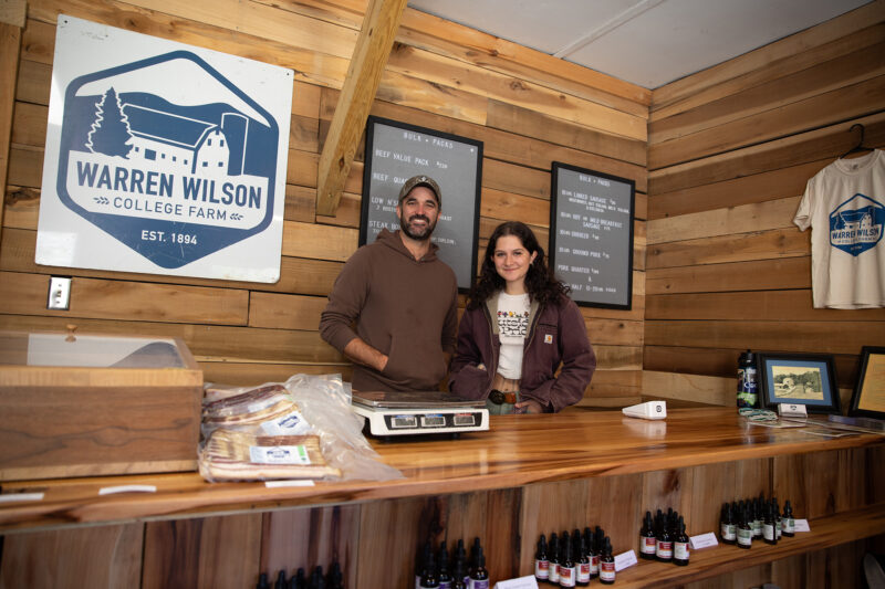 Two people stand smiling behind the counter of the Farm General Store