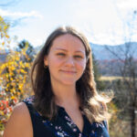 Senior Admissions Counselor Molly Howard stands smiling in front of the College Farm.