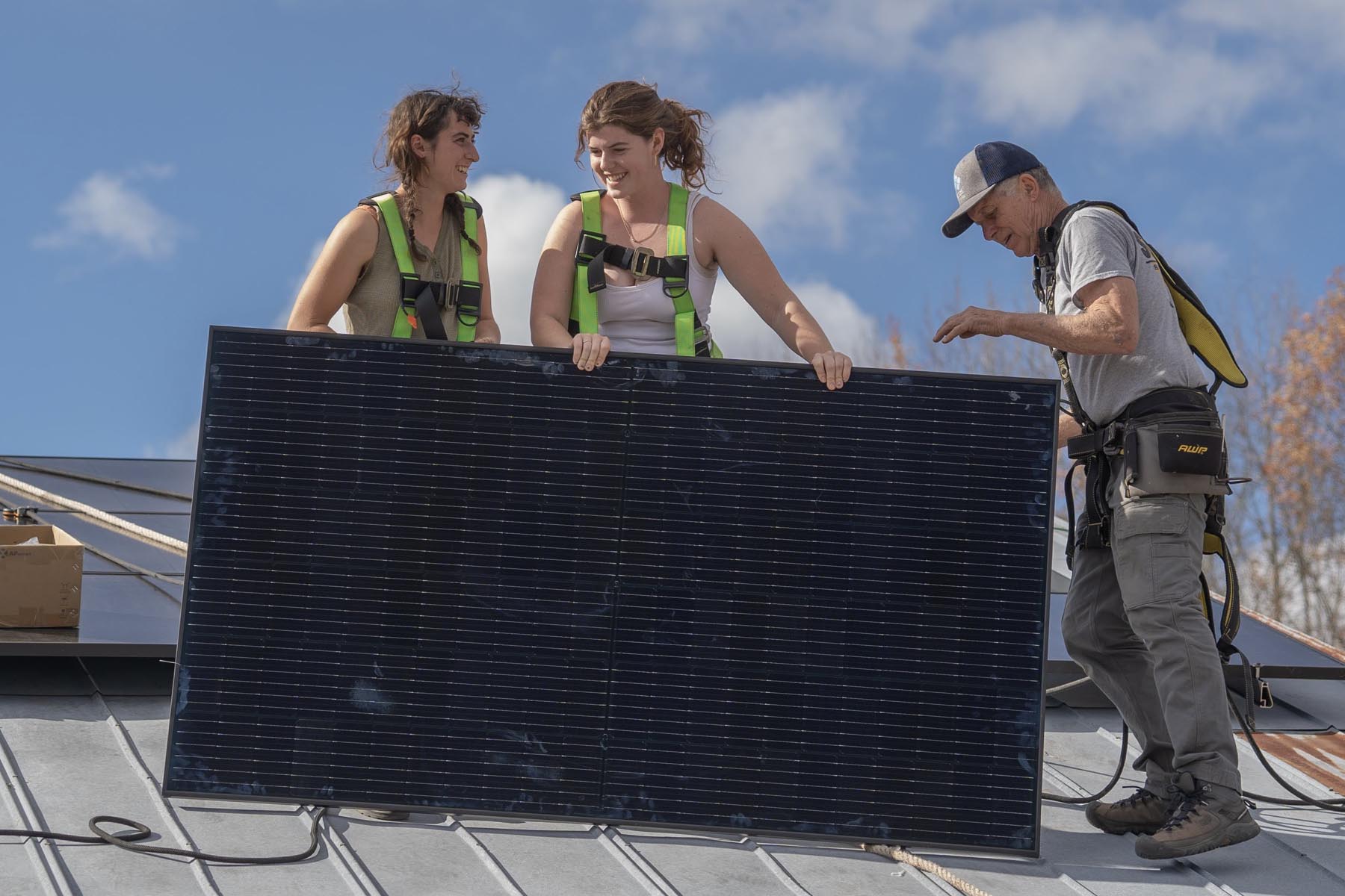Students install a solar panel on the roof of the electric tractor barn.