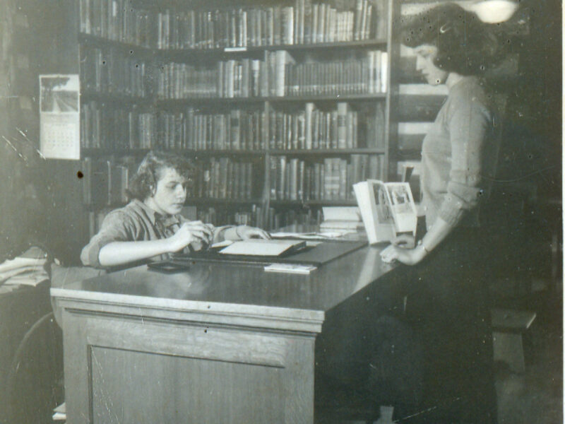 Historical photograph of students in the original log cabin library.